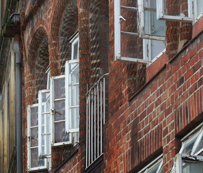 Offene Fenster an historischer Ziegelfassade mit deutlichen Klinker Ausblühungen rund um Laibungen und Fugen